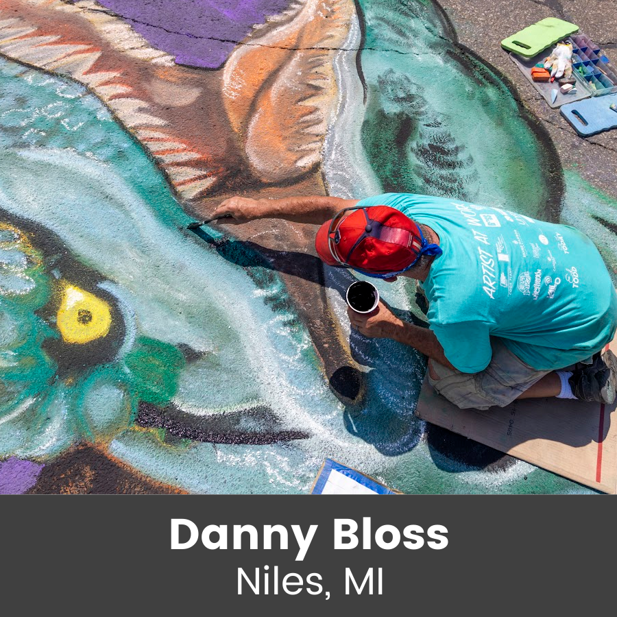 Artist working on chalk art piece - large colorful dinosaur